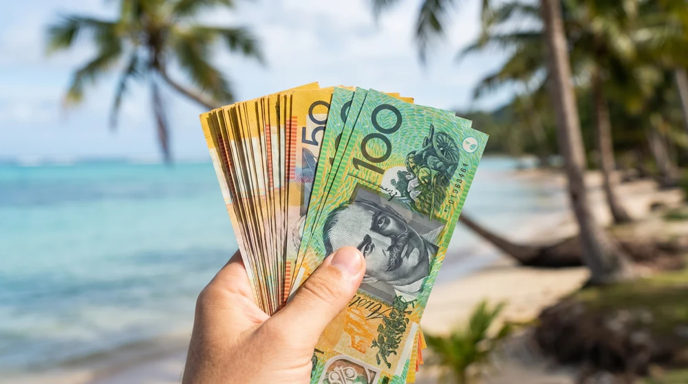 Physical Australian Dollar cash held up against a Pacific island backdrop showing cash-only travel reality in Tuvalu